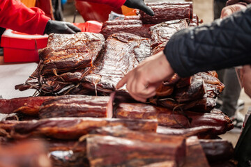 Selective blur on blocks of slanina, a serbian bacon, made of dried cured pork smoked on the stand of countryside market of Serbia with hands buying some. It's a traditional meat product from Balkans.