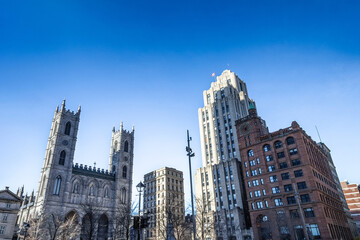 Notre Dame Basilica in the Old Montreal and its iconic towers, with the Aldred Building in backgground. The basilica is the main cathedral of Montreal, and a touristic landmark.