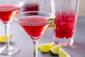 Martini cocktail with cranberry juice garnished with lime twist