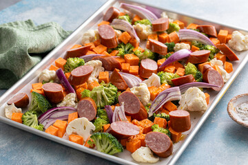 Sheet pan dinner with sausage and vegetables ready to be roasted