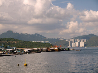 Famous Lamma Island view with floating fishing village and Distant Hong Kong city in background on sunny day