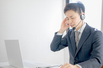 辛そうなヘッドセットの男性