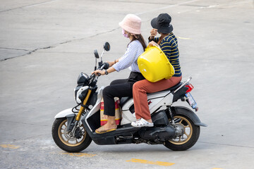 Two women carry cargo on a motorbike, Thailand