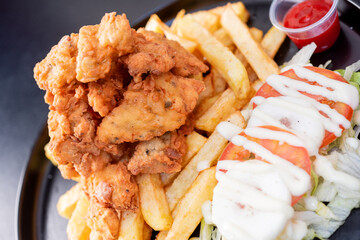 Deep-Fried Chicken chicharr n de pollo , Fried chicken nuggets, French fries and vegetables with chili sauce.