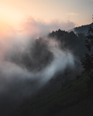 Clouds swirling into a mountain valley at sunset.