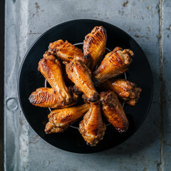 Roasted chicken wings on black plate with barbecue sauce, directly above