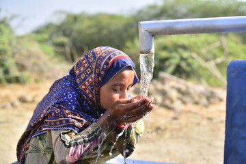 Child Drinking from a Hand Pump. Young Pakistani girl drinking clean water From Hand Pump. Water...