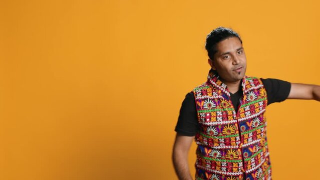 Joyful person having fun, dancing on rhythm, enjoying days off from work. Upbeat indian man entertaining himself doing funky movements, swinging arms, studio background, camera A