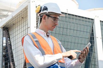 Asia Man engineer using tablet computer at rooftop building construction or working checking HVAC...