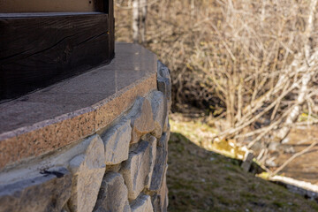 Fragment of a wall made of stones of different sizes. Close-up of a rough stone wall. Part of a stone wall on a sunny day.