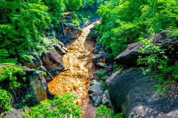Beautiful natural scenery of turbulent muddy water flowing through rock channel in Op Luang...