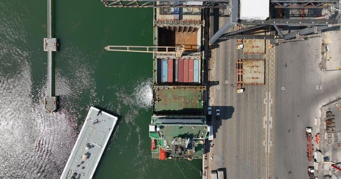Aerial top down view of container ship unloading by big cranes in port. Business logistic import and export freight transportation by container ship
