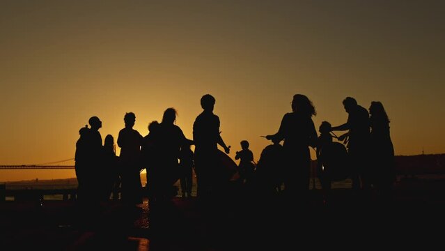 A silhouette - drum players plays music by sticks against a sunset