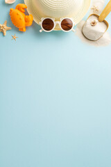 A summer vacation vertical setup with a straw hat, white sunglasses, sandy shovel, and starfish on a pastel blue background, capturing the essence of beach holidays