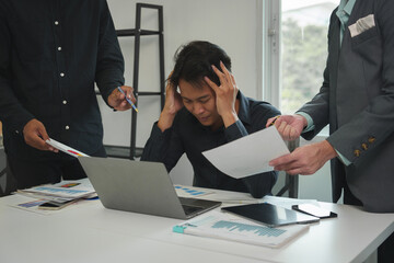 Tired Asian young businessman. Stressed. The man at work has a headache from overwork. Calculating...