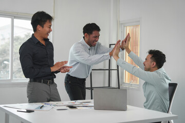 Happy team of young Asian businessmen Congratulate together and celebrate your success in starting your business. Brainstorming meeting of creative team, partners, teamwork concept in office.
