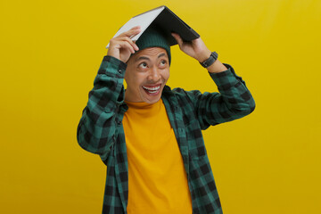 An amazed young Asian student, dressed in a beanie hat and casual clothes, has placed a book over...