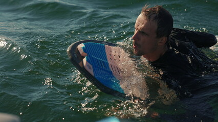 Wakeboarding. A wakeboarder climbs onto a boat after falling into the water. Summer sports on a...