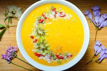 Mango pineapple smoothie bowl made with coconut milk mango pineapple and banana topped with mango toasted coconut and kiwi and goji berry 