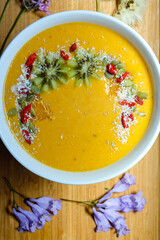 Mango pineapple smoothie bowl made with coconut milk mango pineapple and banana topped with mango toasted coconut and kiwi and goji berry 