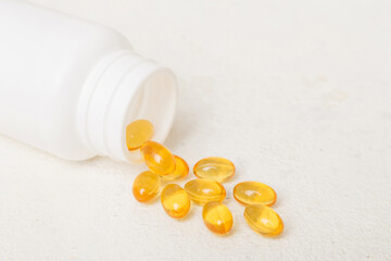 Omega-3 capsules lie in white bottle on a table background. Fish oil tablets top view. Biologically...