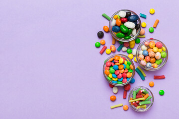 different colored round candy in bowl and jars. Top view of large variety sweets and candies with...