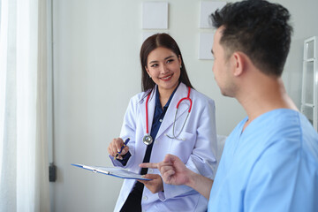 Physiotherapist giving advice and encouragement to male patient doing physiotherapy lying on...