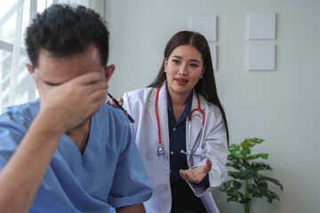 A professional female doctor in a white robe spoke. Has a heart rate stethoscope around his neck. Talking with a male patient about stress symptoms headache to plan treatment at hospital bed