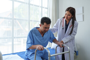Physical therapist helps a male patient use a walker to practice walking. Support yourself from recovery from sore legs and ankles. Physical therapy service concept.