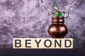 Word BEYOND made with wood building blocks on a gray back ground