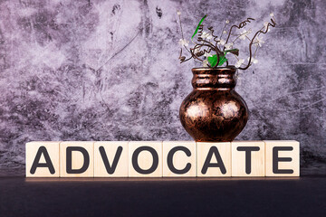 ADVOCATE word made with building blocks on a grey background.