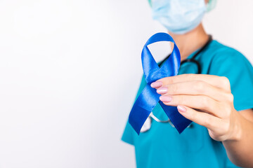 Doctor holding blue awareness ribbon, closeup view. Symbol of medical issues