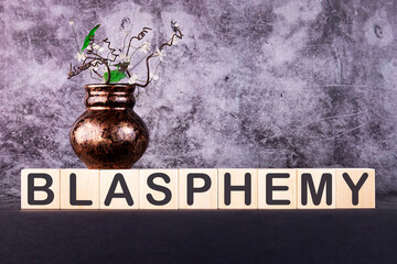 BLASPHEMY word made with building blocks on a grey background