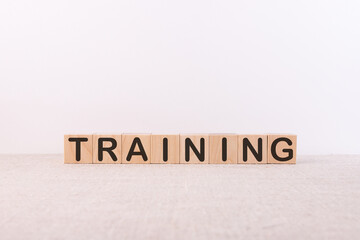 TRAINING word concept written on wooden cubes lying on a light table and light background.
