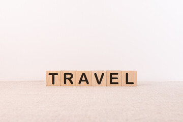 TRAVEL word concept written on wooden cubes blocks lying on a light table and light background