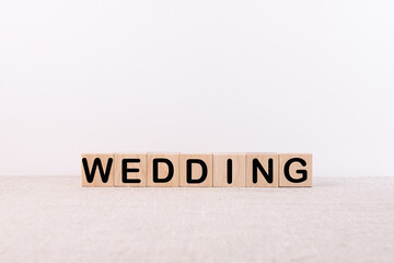 WEDDING word concept written on wooden cubes blocks lying on a light table and light background