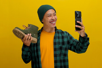 Asian man in a beanie and casual clothes excitedly shows off his new shoes in a selfie. Just bought...