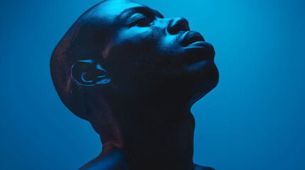 A stark photo of a man bathed in blue light, showcasing a contemplative and serene expression