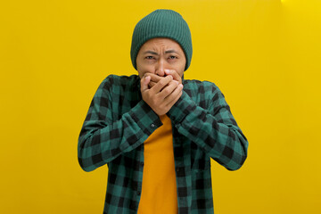 Unwell young Asian man, dressed in a beanie hat and casual outfit, is seen coughing and appears to...