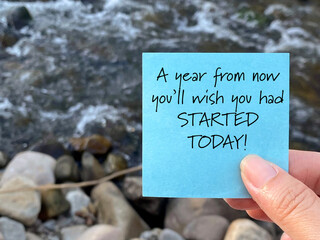 A year from now you'll wish you had started today text note on paper with nature background. Stock photo.