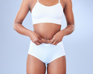 Woman, body fat and lose weight with underwear for diet or nutrition on a blue studio background....