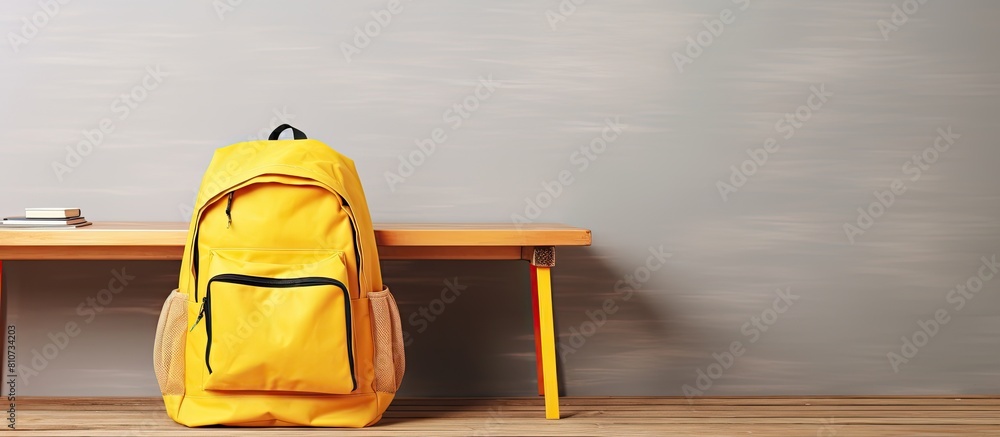 Aufkleber Copy space image of a yellow backpack filled with school supplies placed on a wooden table providing an empty background for potential usage