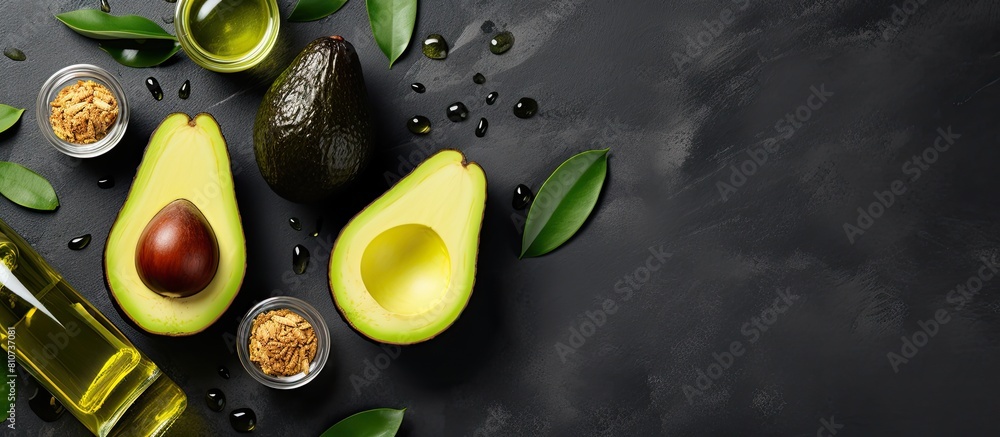 Poster top view copy space image of bottles containing avocado oil alongside slices of avocado on a grey ba
