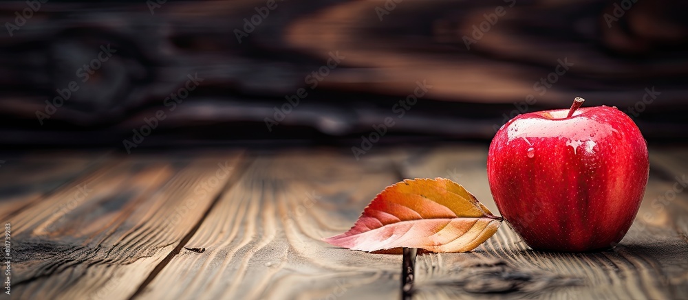 Poster a red apple is seen in the foreground placed on a rustic wooden surface surrounded by dry leaves the