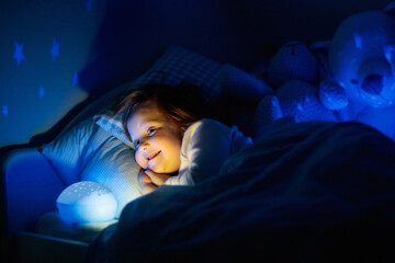 Little girl reading a book in bed