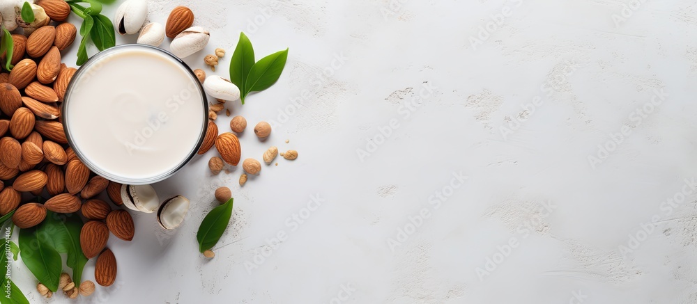 Leinwandbilder top view of a cup filled with almond milk surrounded by nuts and a potted plant placed on a white co