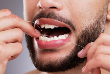 Man, cleaning and teeth with floss in studio for oral hygiene, mouth care and fresh breath. Male person, morning routine and hand with dental product for gum health, protection and cavity prevention