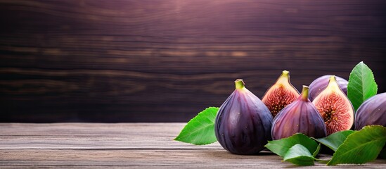 A wooden table is adorned with luscious purple figs offering plenty of room for copy space image