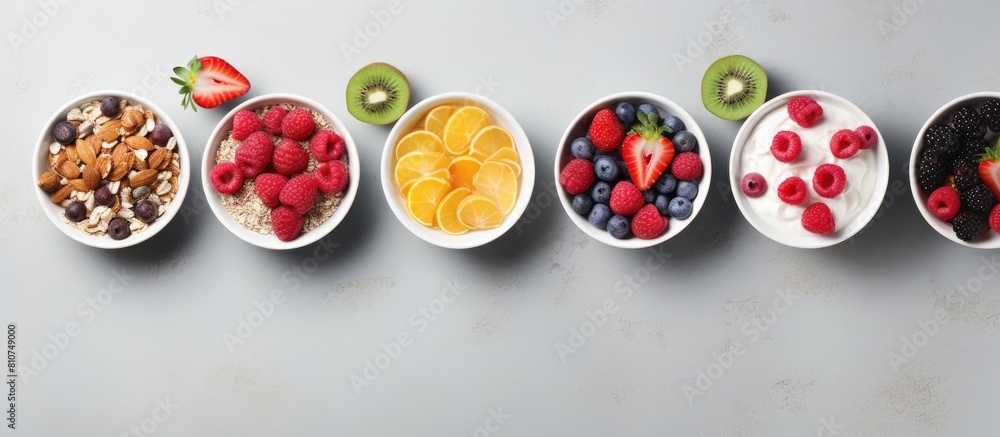 Poster top view of a collection of bowls filled with granola yogurt and berries placed on a grey background