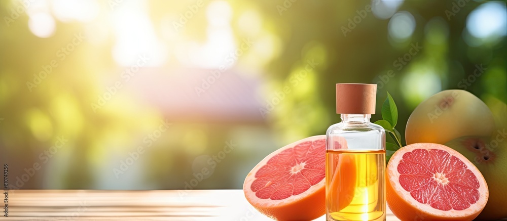 Fototapete Close up photo of grapefruit essential oil in a bottle alongside a fresh fruit placed on a well lit table There is empty space available for adding text. Creative banner. Copyspace image